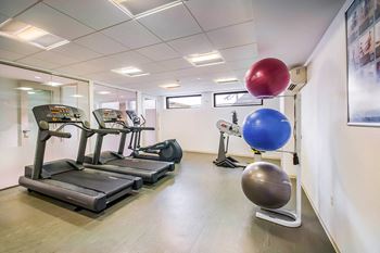 A gym with treadmills, exercise balls, and a mirror.